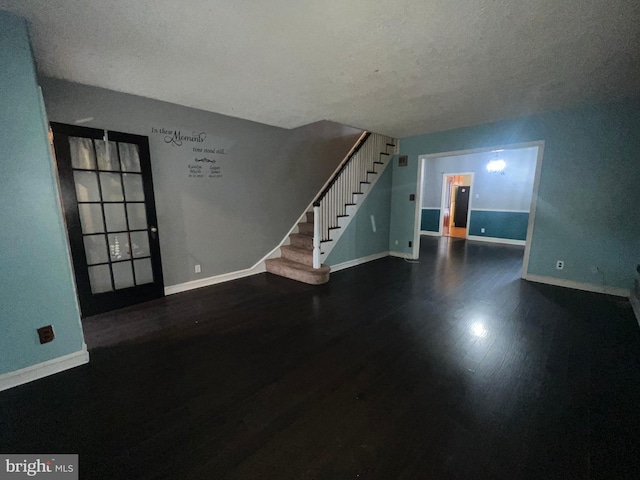 spare room featuring a textured ceiling and dark hardwood / wood-style flooring