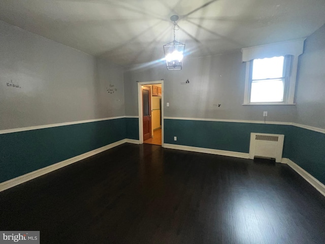 unfurnished room featuring radiator and hardwood / wood-style floors