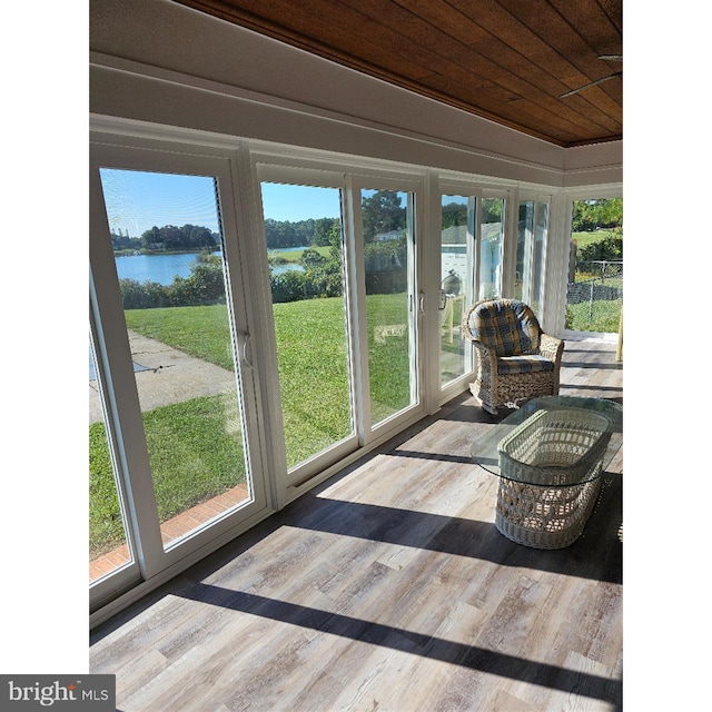 sunroom with wood ceiling, a wealth of natural light, a water view, and vaulted ceiling