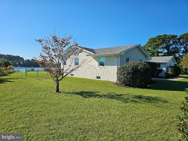 view of side of home with a water view and a yard