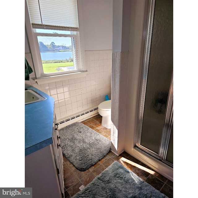 bathroom featuring a water view, baseboard heating, a shower with shower door, vanity, and toilet