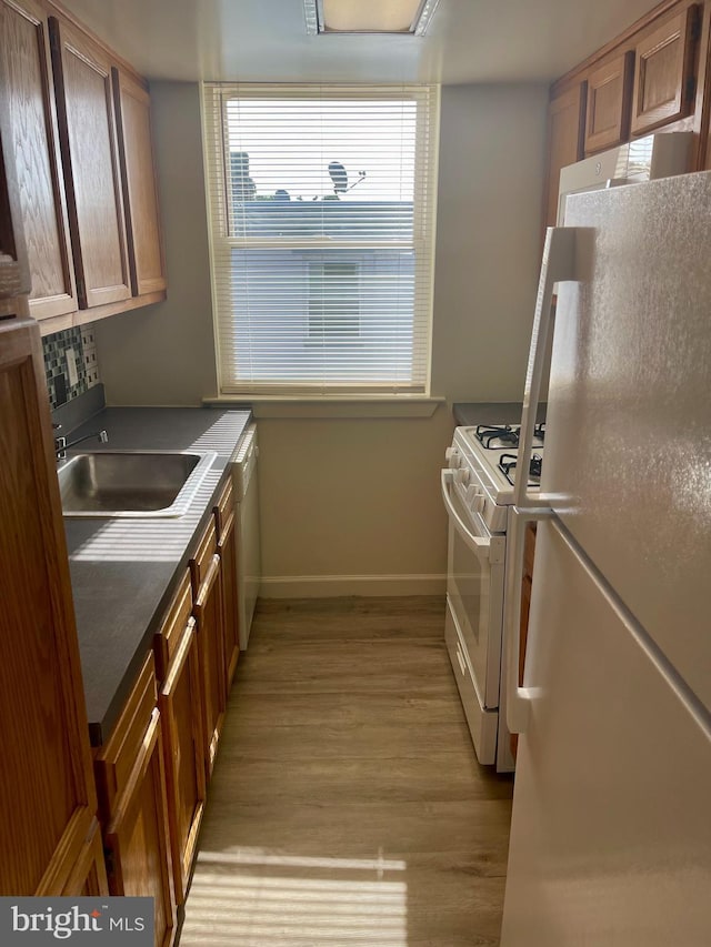 kitchen featuring white appliances, light hardwood / wood-style floors, and sink