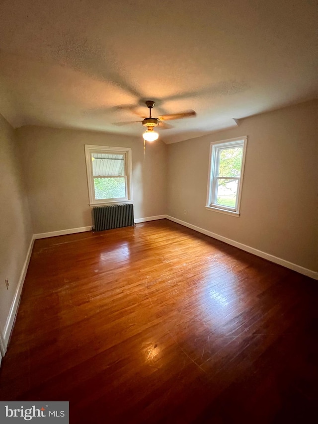 unfurnished living room with wood-type flooring, a textured ceiling, radiator heating unit, and ceiling fan