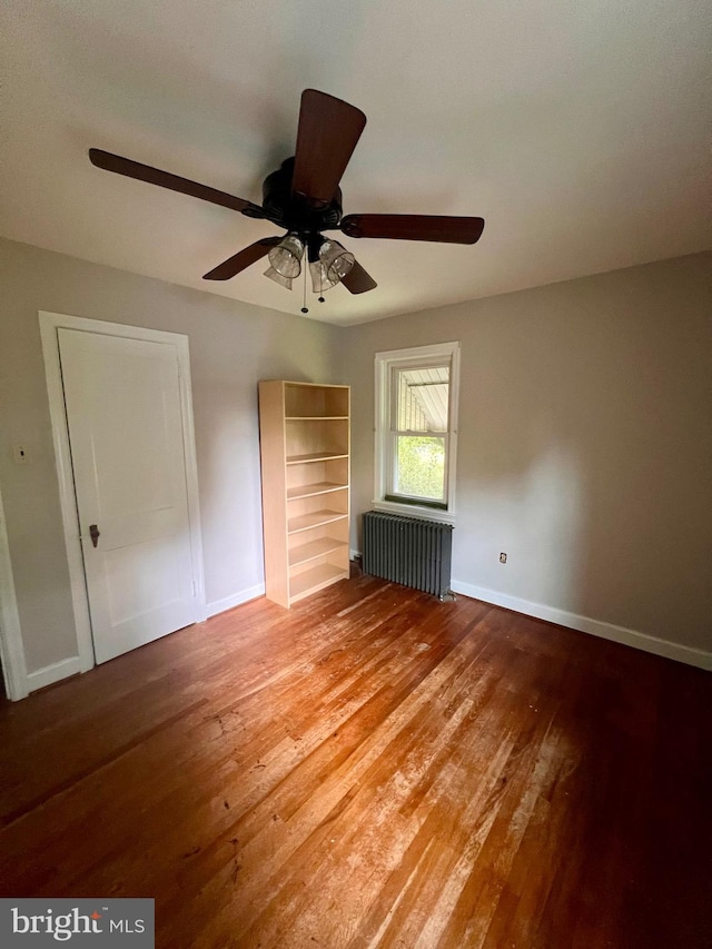 unfurnished bedroom featuring wood-type flooring, radiator, and ceiling fan