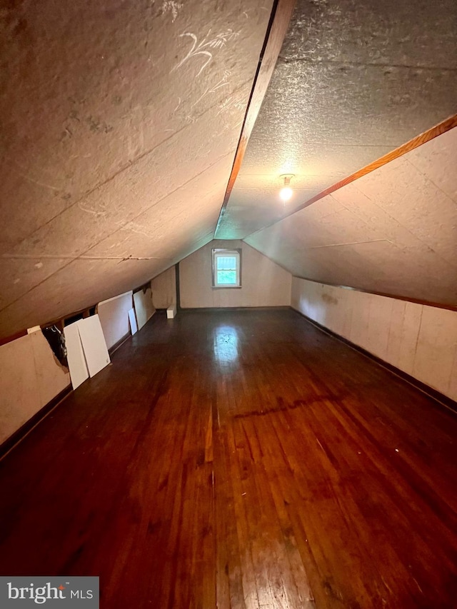 bonus room with a textured ceiling, lofted ceiling, and hardwood / wood-style flooring