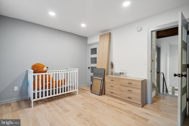 bedroom featuring light wood-type flooring and a nursery area