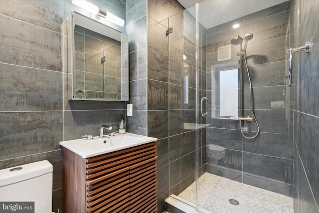 bathroom with vanity, toilet, walk in shower, and tile walls