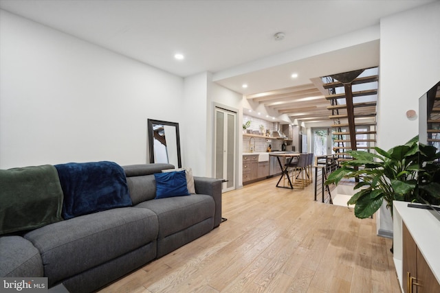 living room with beamed ceiling and light wood-type flooring