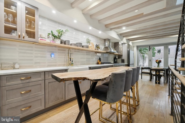 bar with beam ceiling, tasteful backsplash, butcher block counters, wall chimney exhaust hood, and sink