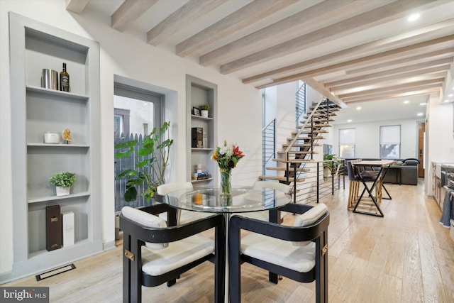 dining area featuring beam ceiling, a wealth of natural light, light wood-type flooring, and built in shelves