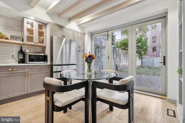 dining space with light hardwood / wood-style floors and beamed ceiling