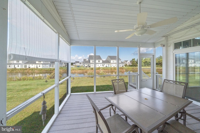 unfurnished sunroom with ceiling fan and a water view