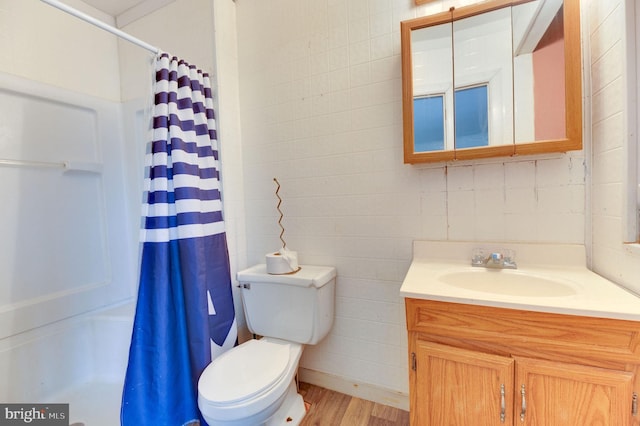 bathroom featuring hardwood / wood-style floors, vanity, toilet, walk in shower, and tile walls