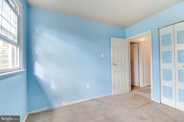 unfurnished bedroom with light colored carpet and a closet