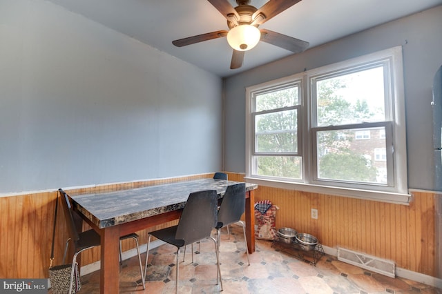 office space with ceiling fan and wood walls