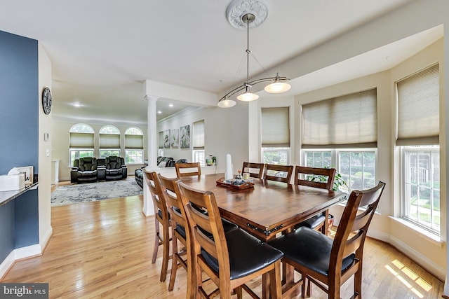 dining space featuring light hardwood / wood-style floors and decorative columns