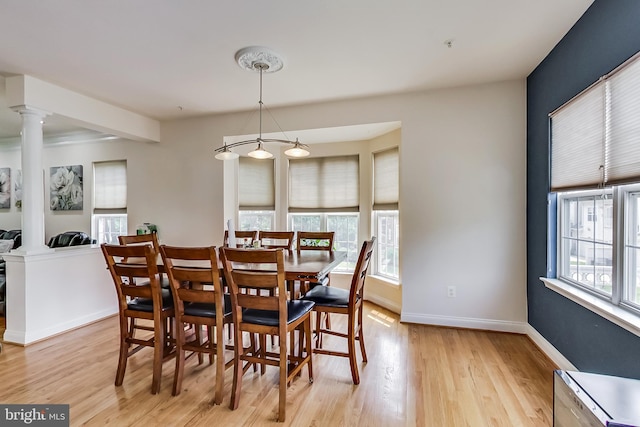 dining area featuring light wood-type flooring, ornate columns, and a wealth of natural light