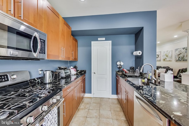 kitchen featuring sink, light tile patterned floors, stainless steel appliances, and dark stone counters