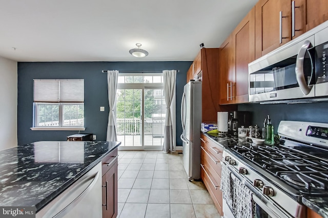 kitchen featuring light tile patterned floors, stainless steel appliances, and dark stone counters