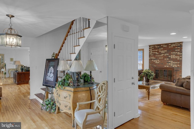 stairway with hardwood / wood-style floors, a chandelier, and a fireplace