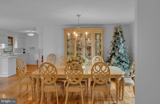 dining room featuring sink, light hardwood / wood-style flooring, and a notable chandelier