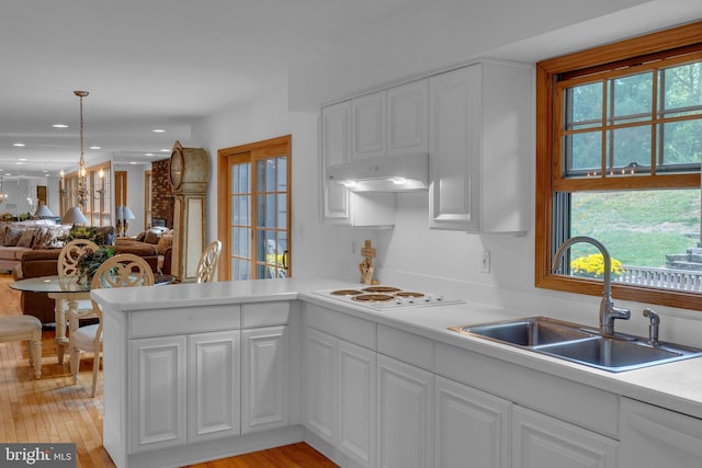 kitchen featuring light wood-type flooring, white cabinets, sink, and a notable chandelier