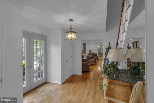 entrance foyer with a chandelier, light hardwood / wood-style floors, and french doors