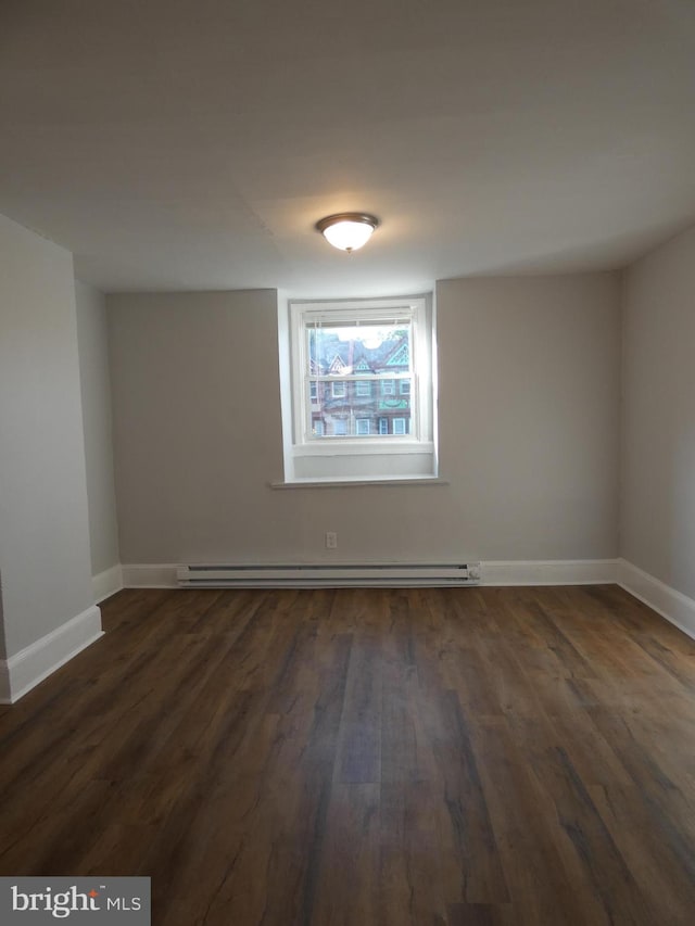 unfurnished room with dark hardwood / wood-style flooring and a baseboard heating unit