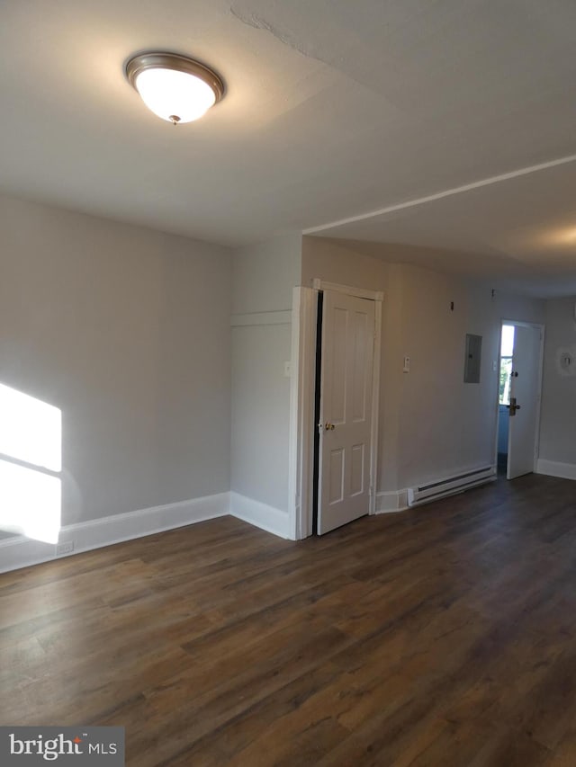 spare room featuring a baseboard radiator, electric panel, and dark wood-type flooring