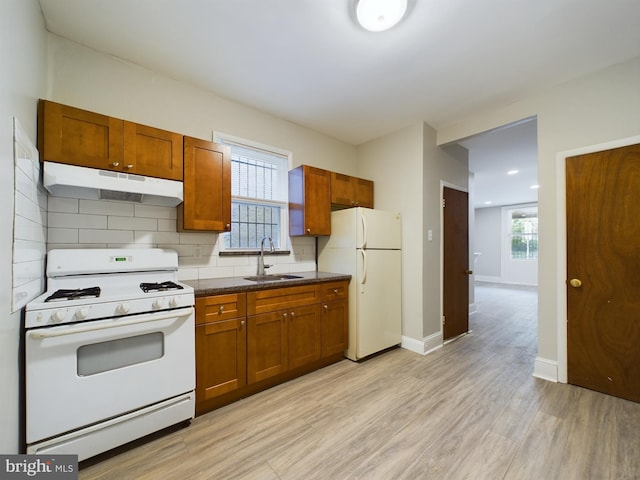 kitchen featuring a wealth of natural light, white appliances, light wood-type flooring, and sink