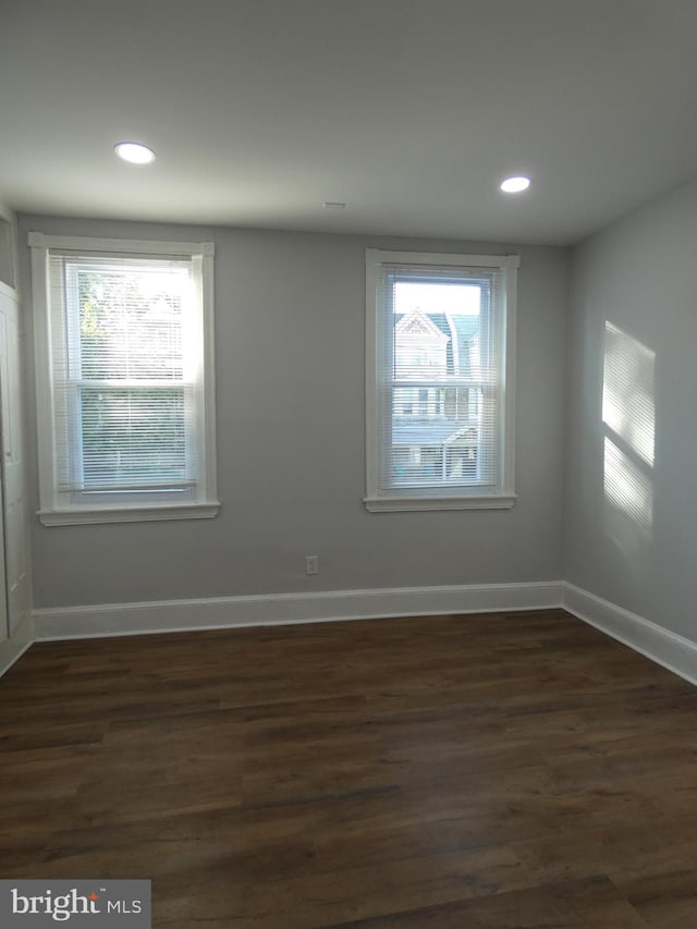 empty room with plenty of natural light and dark wood-type flooring