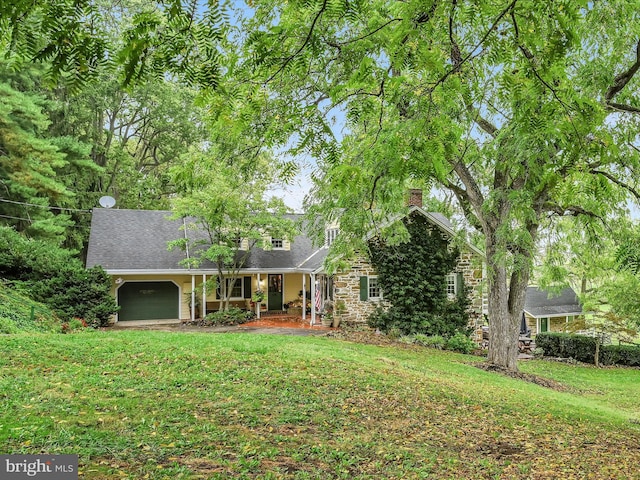 view of front of property featuring a garage, a front yard, and a porch