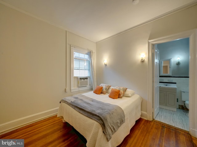 bedroom featuring cooling unit, ornamental molding, connected bathroom, and dark hardwood / wood-style flooring