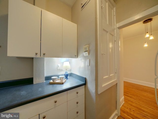 kitchen featuring hanging light fixtures, light hardwood / wood-style flooring, and white cabinets