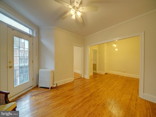 spare room featuring ceiling fan, ornamental molding, radiator heating unit, french doors, and light wood-type flooring