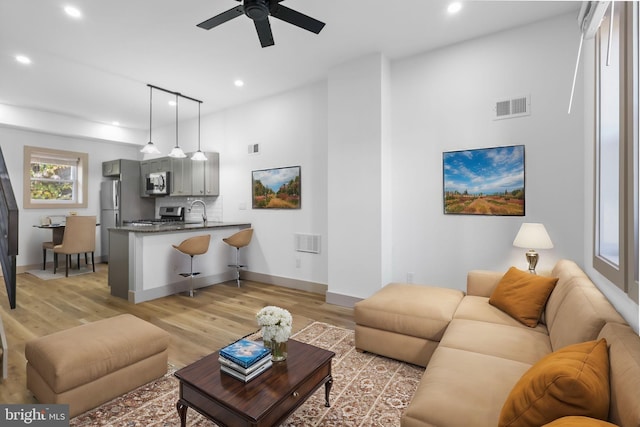 living room featuring sink, ceiling fan, and light hardwood / wood-style flooring