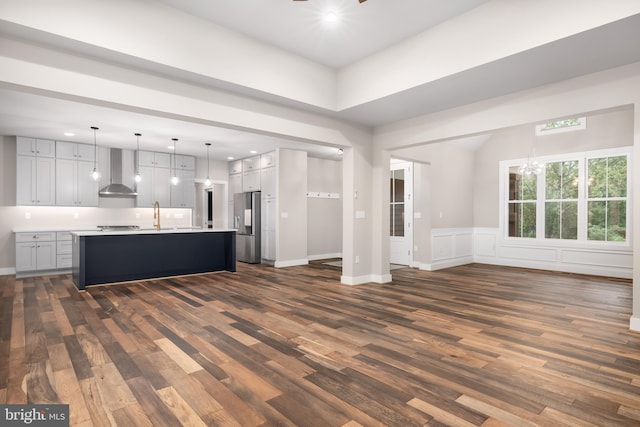 unfurnished living room featuring an inviting chandelier, sink, and dark hardwood / wood-style flooring