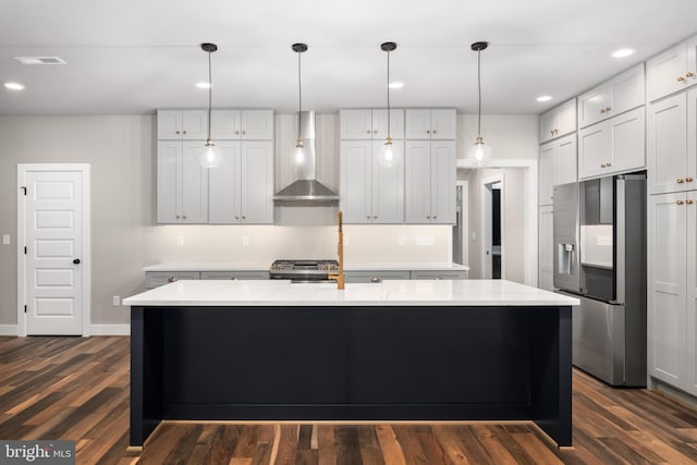 kitchen with a center island with sink, appliances with stainless steel finishes, dark hardwood / wood-style floors, and wall chimney range hood