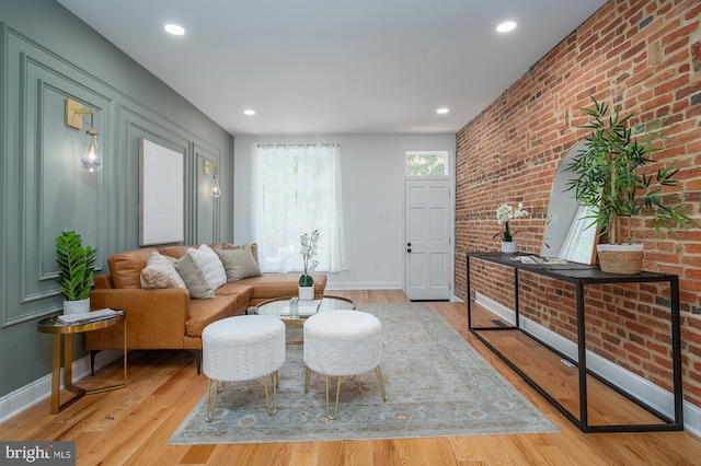 living room with brick wall and light wood-type flooring