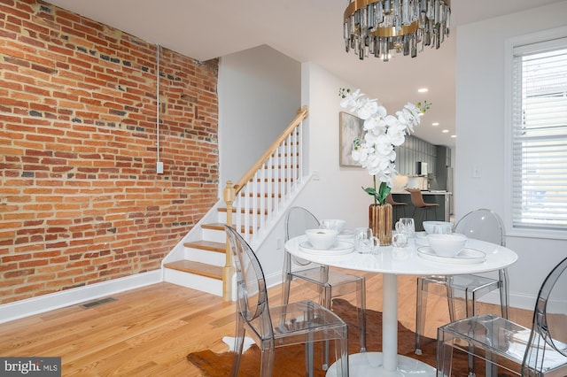 dining space featuring a wealth of natural light, brick wall, a chandelier, and light hardwood / wood-style floors