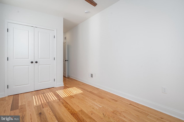 unfurnished bedroom with a closet, light wood-type flooring, and ceiling fan