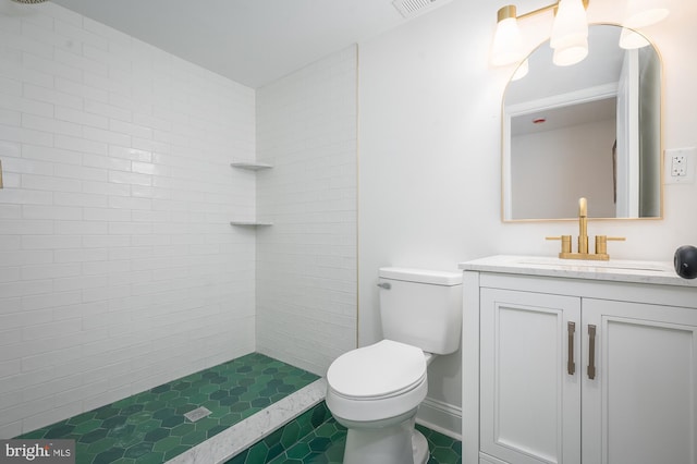 bathroom featuring vanity, toilet, tile patterned floors, and tiled shower