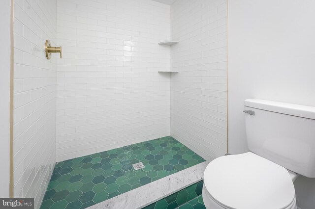 bathroom featuring a tile shower and toilet