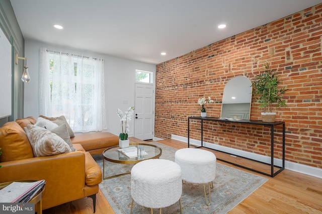 living room featuring brick wall and light wood-type flooring