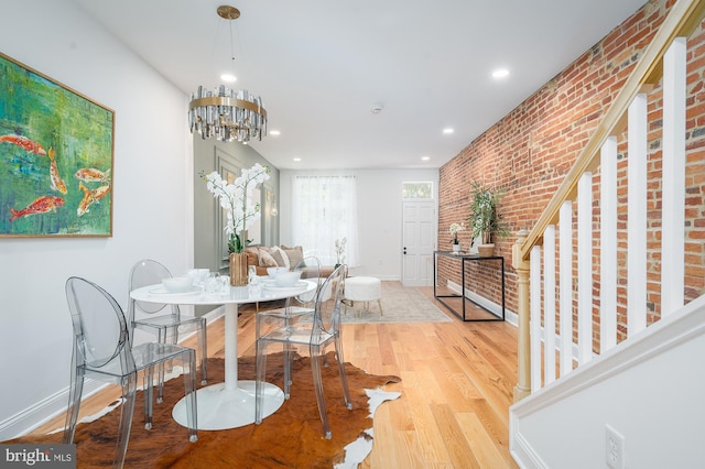 dining area with brick wall and wood-type flooring