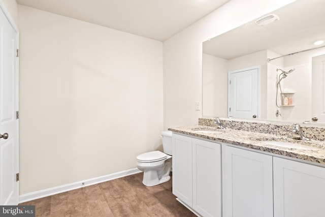 bathroom with toilet, vanity, hardwood / wood-style floors, and a tile shower