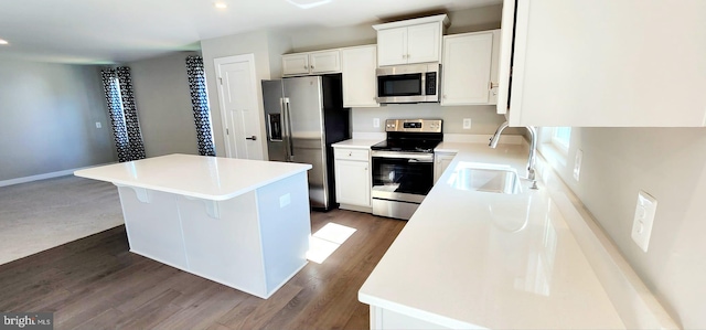 kitchen with a kitchen island, dark hardwood / wood-style floors, stainless steel appliances, sink, and white cabinetry