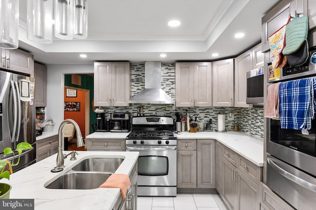 kitchen with wall chimney exhaust hood, tasteful backsplash, stainless steel appliances, and sink