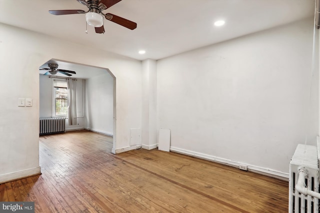 spare room featuring wood-type flooring, radiator, and ceiling fan