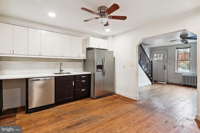 kitchen featuring radiator heating unit, stainless steel appliances, ceiling fan, and light wood-type flooring